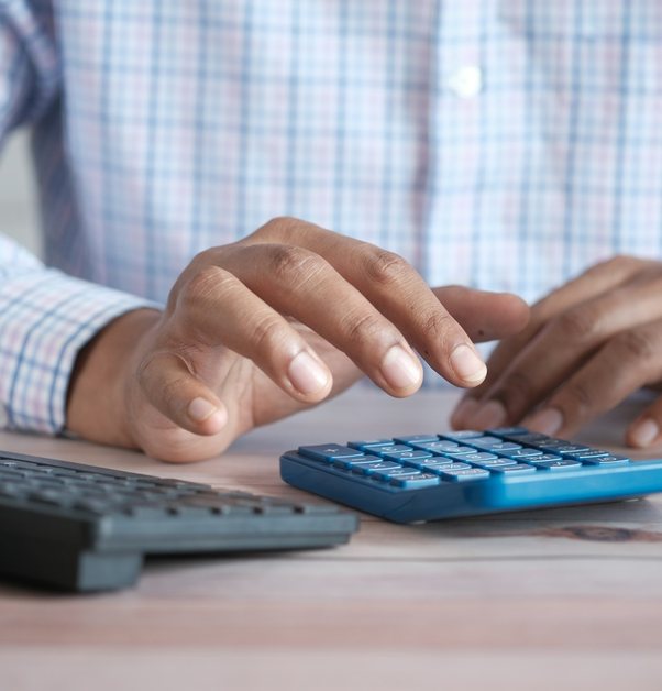 hands working a desk calculator beside a keyboard