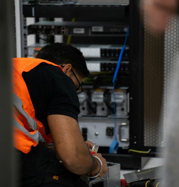 a technician patching cables into a server rack